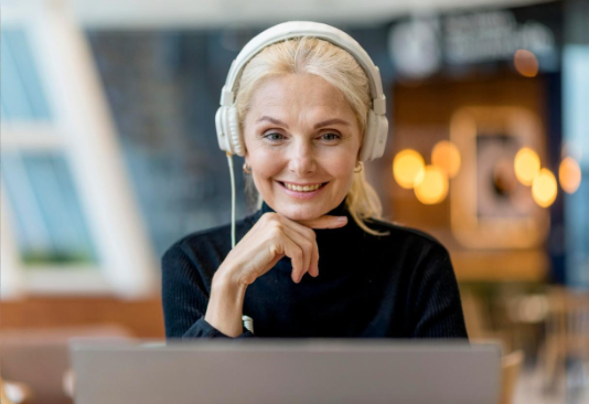 Woman with headphones smiling at laptop